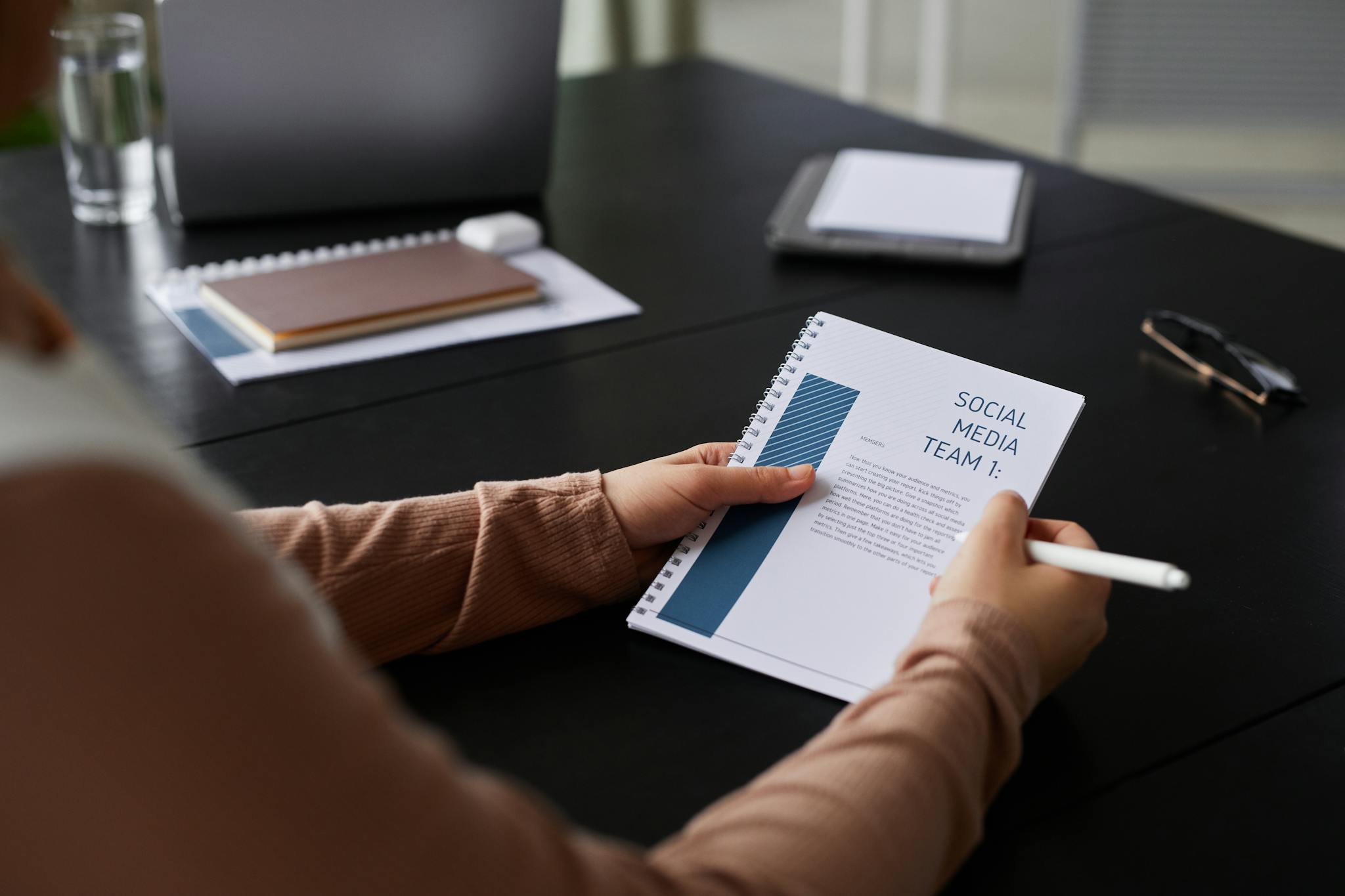 Close-up of a businesswoman holding a social media team notebook in a professional setting.